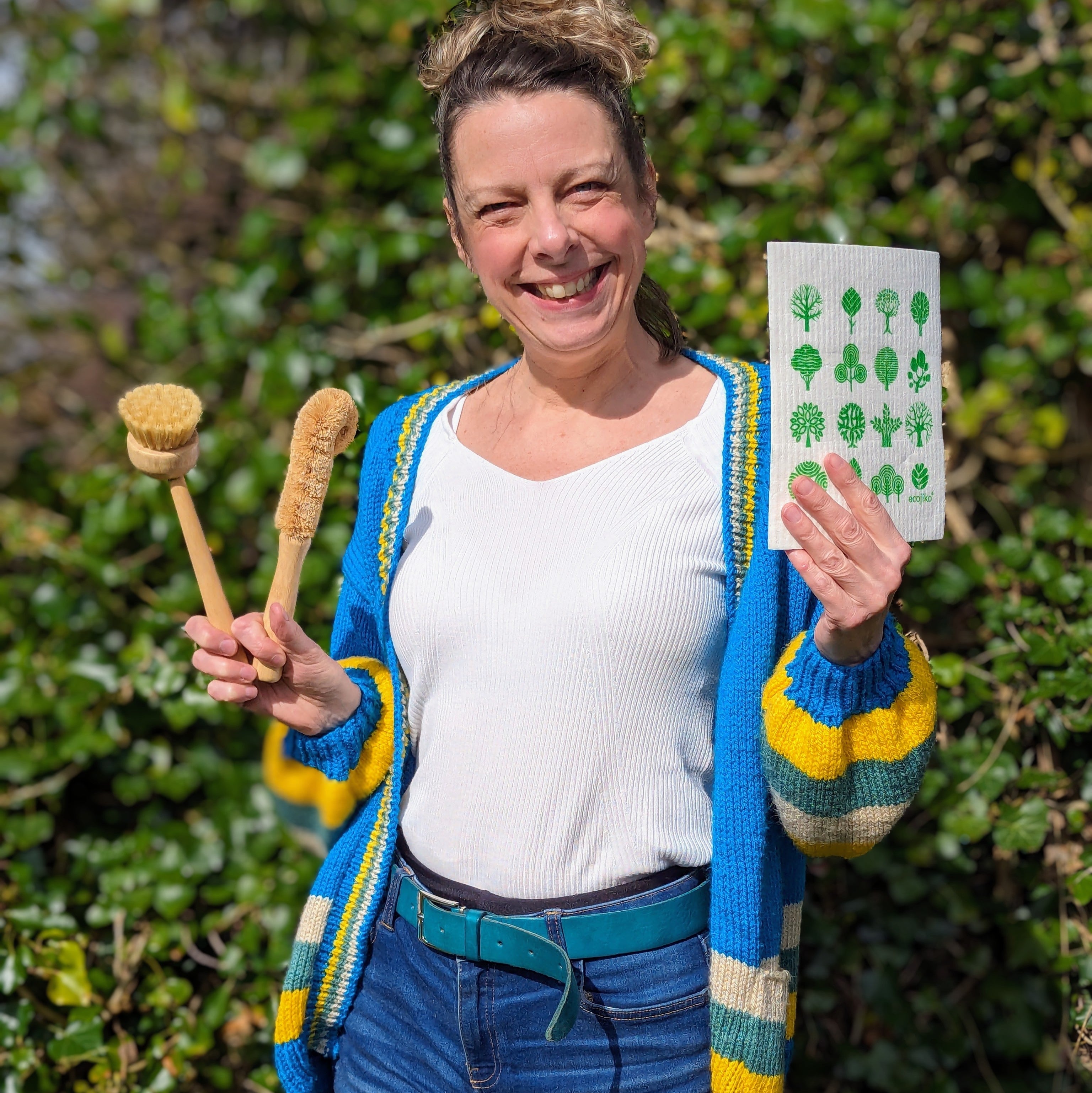 Katy Davies founder of ecojiko holding plastic free dish brushes and compostable cloth in garden