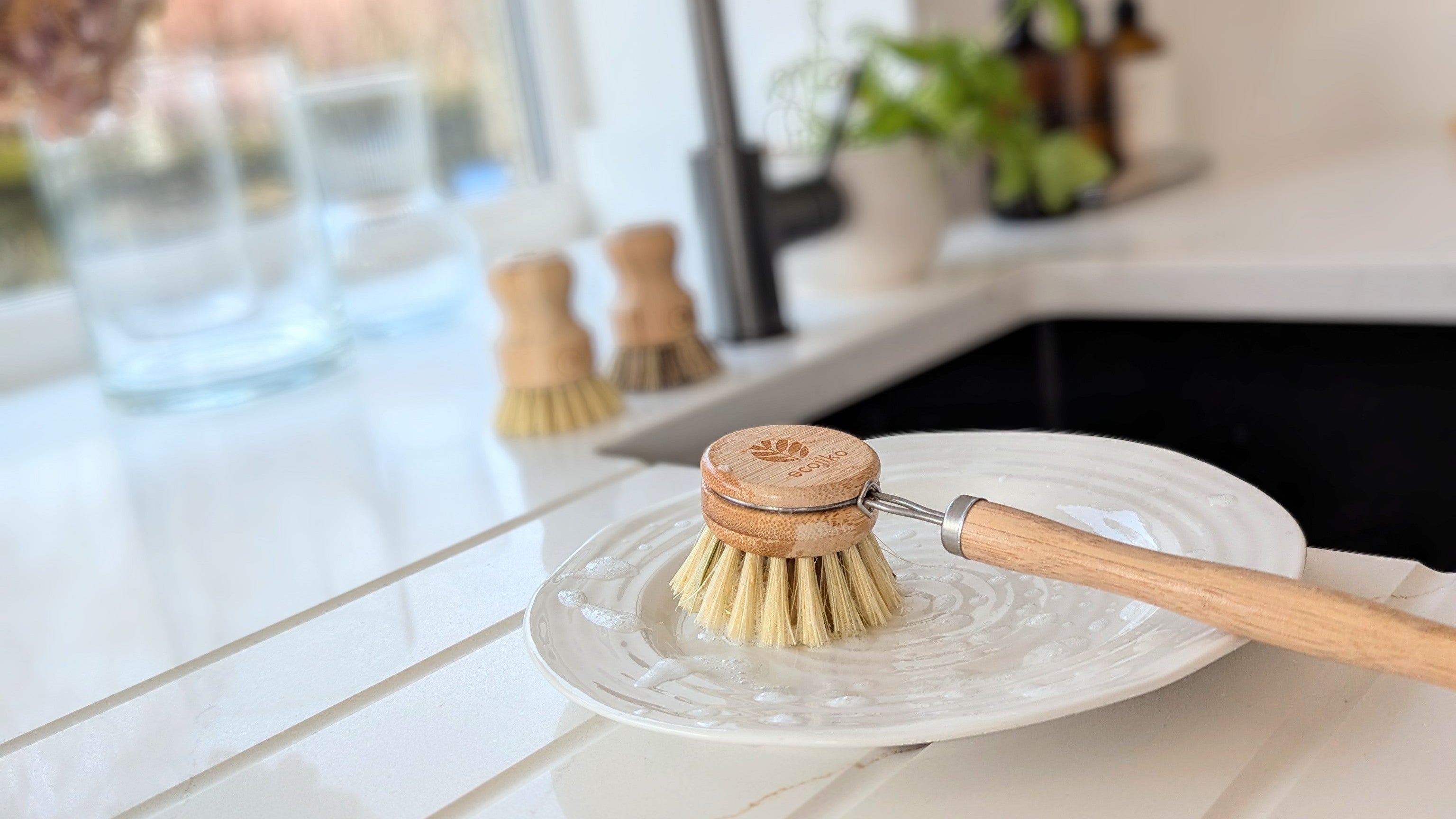 Kitchen sink with dishwashing brush and soap on a white countertop